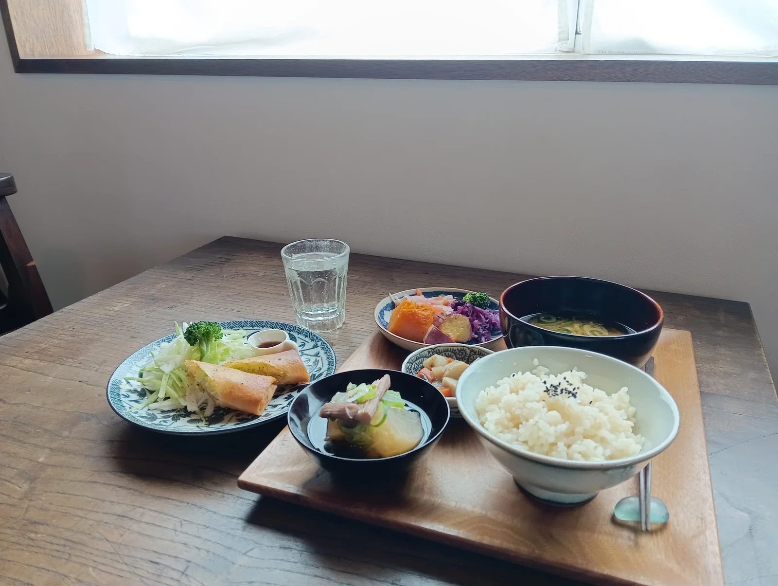 春巻や季節の野菜、ごはんと汁ものを並べた昼食
